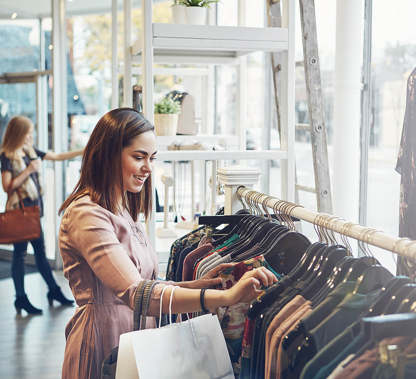 4-store-fulfillment-1396x1272-c.jpg Shopper looking through a clothes rack
