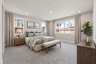 bedroom with tan carpet, wood dresser & nightstands, tan upholstered bed with sage green bedding, and multiple windows