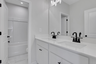 secondary bathroom with white cabinets and tile flooring