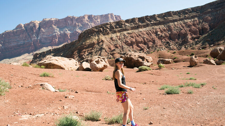 A young traveler explores the red desert landscape of the Grand Canyon in Arizona with majestic rock formations in the background.