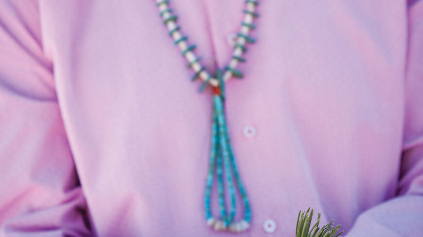 A person in a turquoise necklace holds pine sprigs during a Native American holiday ceremony in Santa Fe, New Mexico.