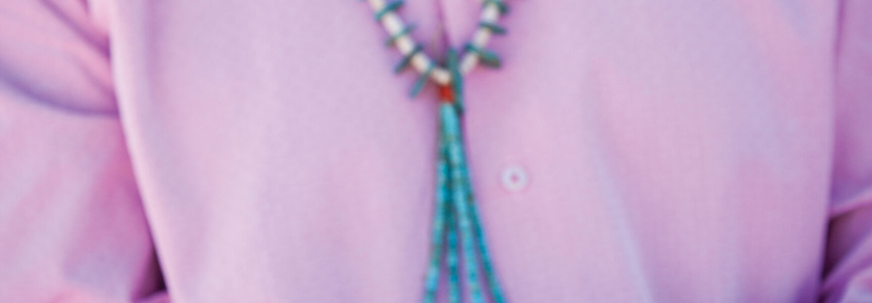 A person in a turquoise necklace holds pine sprigs during a Native American holiday ceremony in Santa Fe, New Mexico.