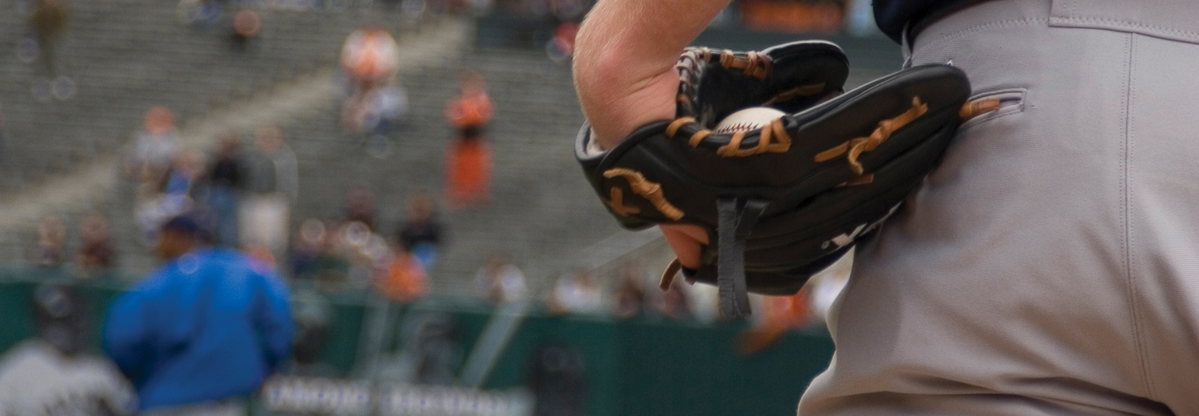 A close-up of a San Francisco Giants player holding a baseball in his glove, with the stadium stands visible in the background in Arizona.