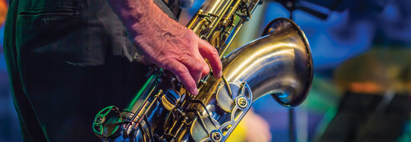 A musician wearing red suspenders plays a brass saxophone during a performance at Monterey's Jazz Bash by the Bay in California.