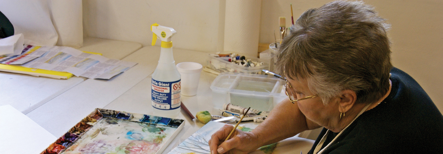 A woman carefully paints with watercolors at a desk during an art workshop in Georgia.