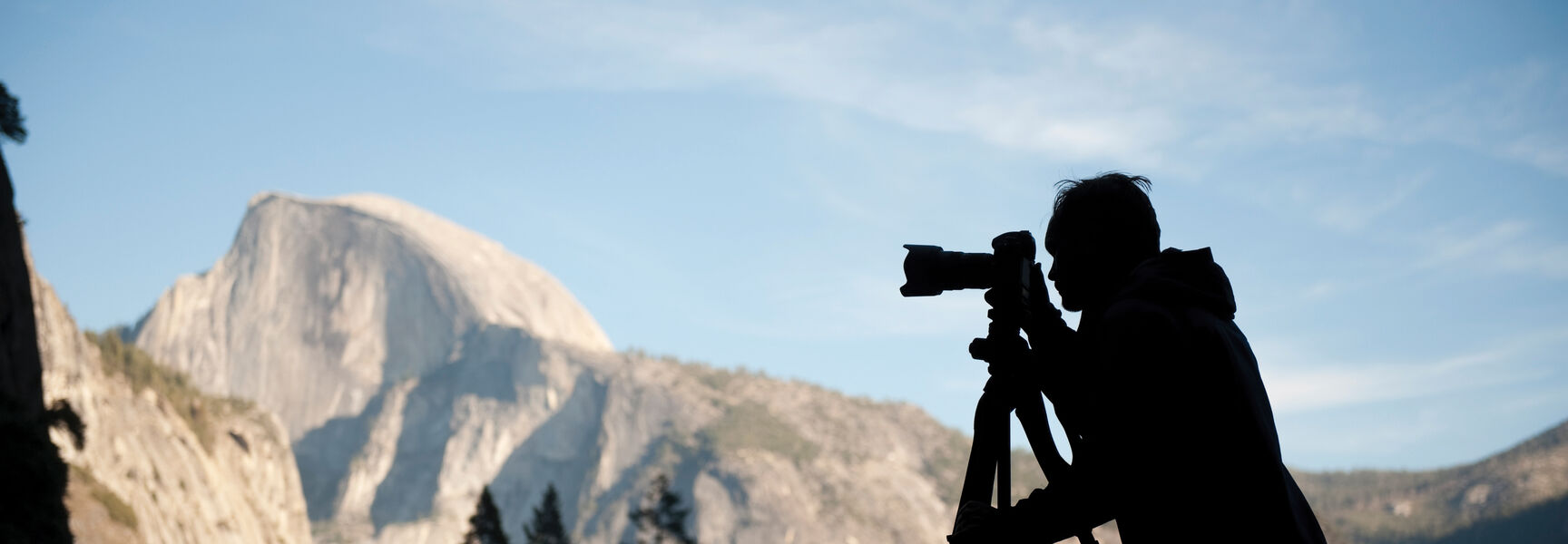 Silhouette of a photographer with a tripod-mounted camera capturing Half Dome in Yosemite National Park, California.