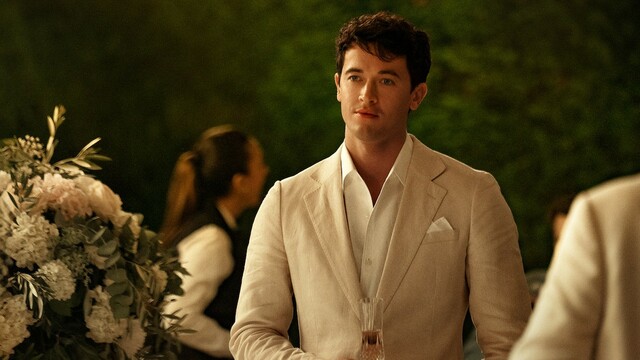 Tom Blyth as Alex Nilsen People from We Meet on Vacation Photo in a suit holding champagne