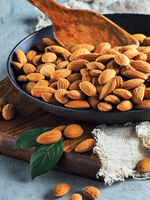 Peeled almond kernels lie in a black frying pan.