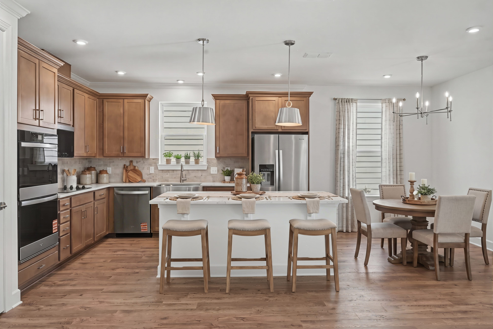 kitchen with wood cabinets, white countertops, stainless steel appliances, barstools, and dining table