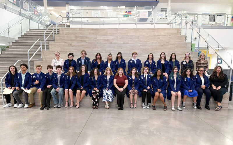 Students pose for the camera in dark blue lab coats.