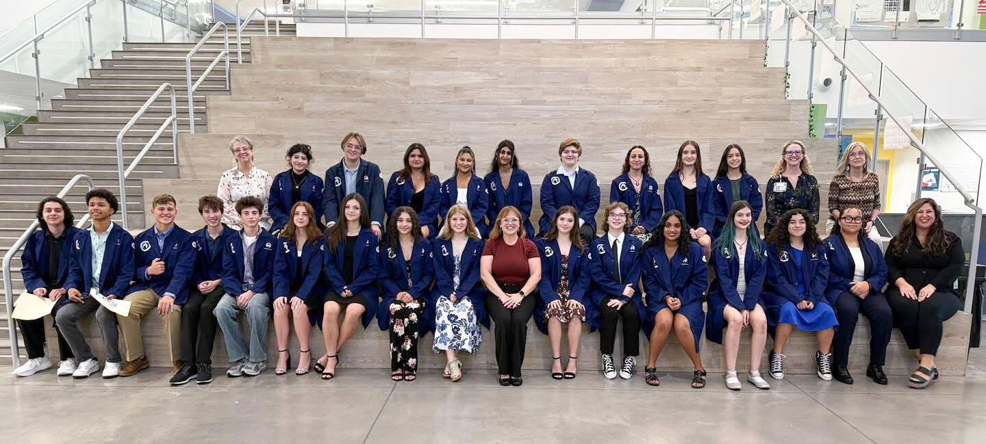 Students pose for the camera in dark blue lab coats.