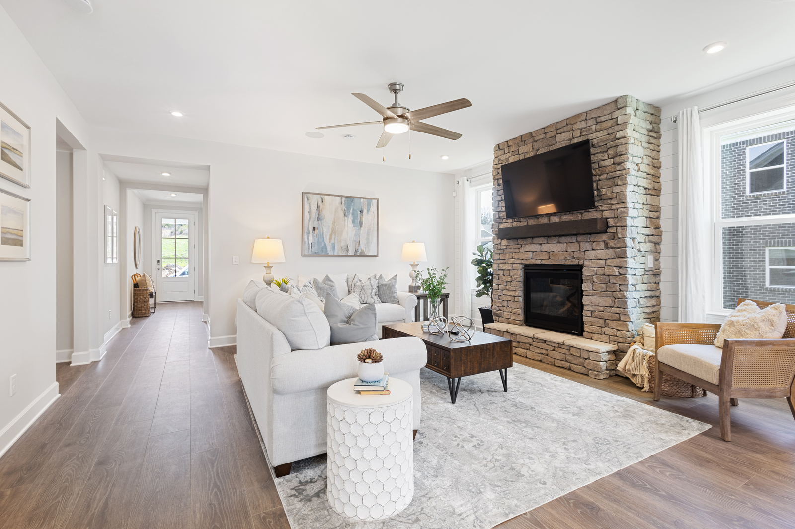 great room with wood floors, large windows, and stone fireplace