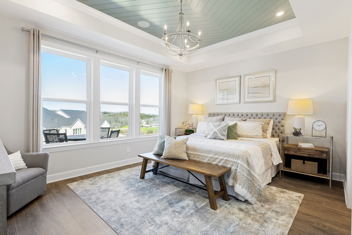 bedroom with tray ceiling and large windows