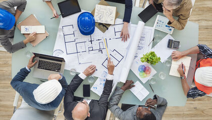Group of architects and engineers looking over building plans 