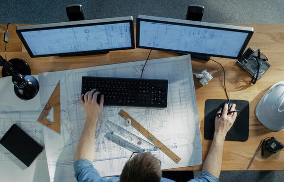 Top-down view of an engineer sitting at a desk and working on a computer