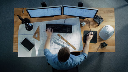 Top-down view of an engineer sitting at a desk and working on a computer