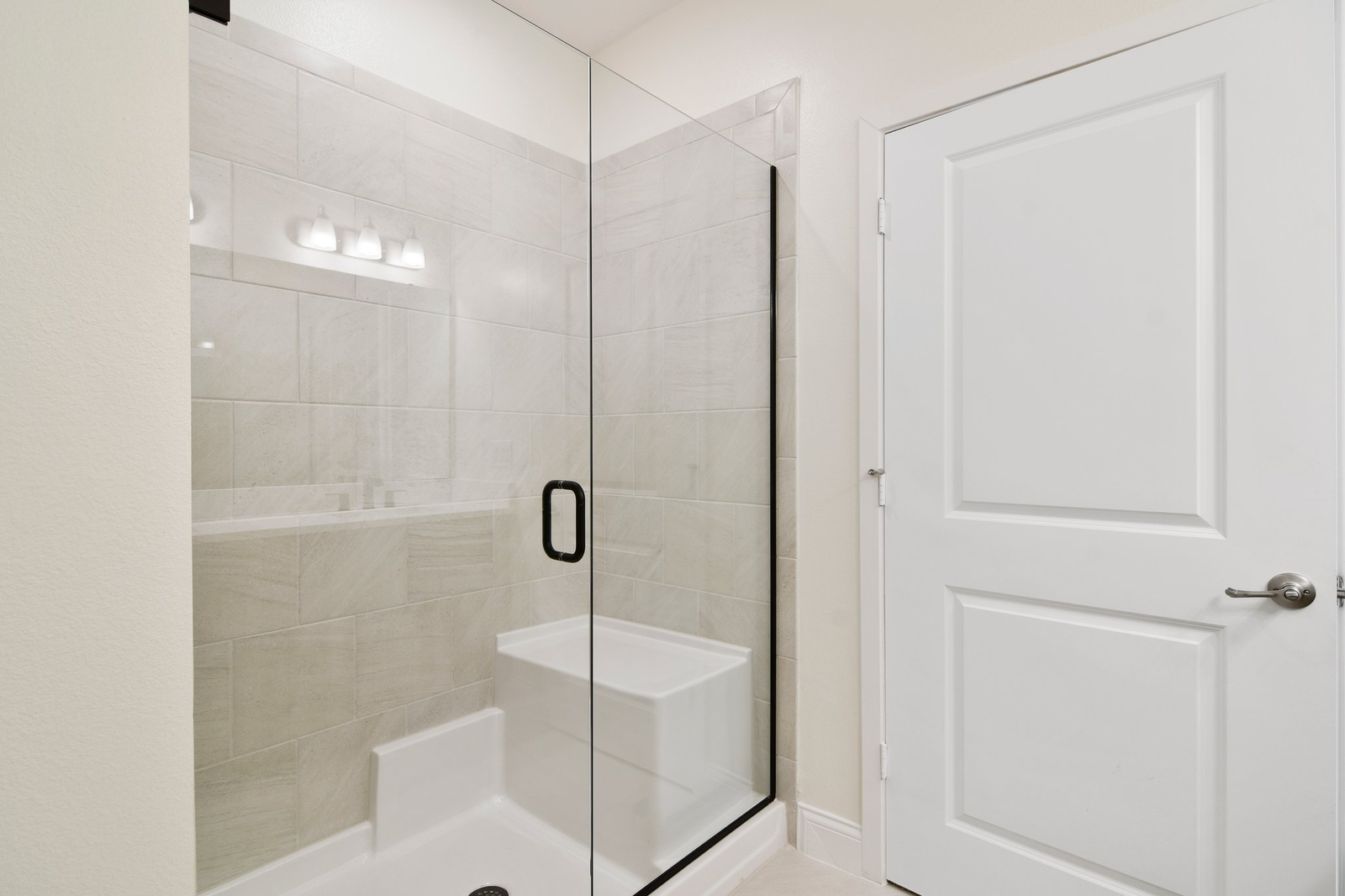 primary bathroom with tile shower and dual vanity sinks