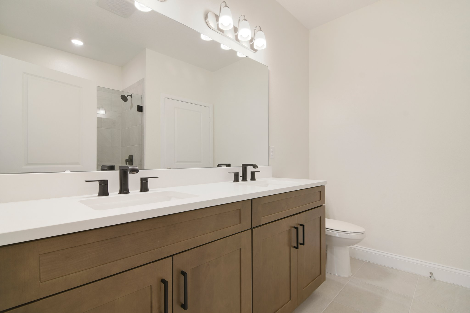 primary bathroom with tile shower and dual vanity sinks