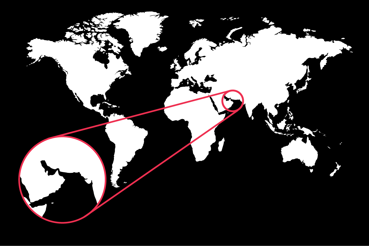 A black and white world map silhouette. A red line connects a small circle over the Middle East to a larger magnified circular callout in the bottom left. The magnified area specifically highlights the Persian Gulf, the Arabian Peninsula, and the Gulf of Oman.