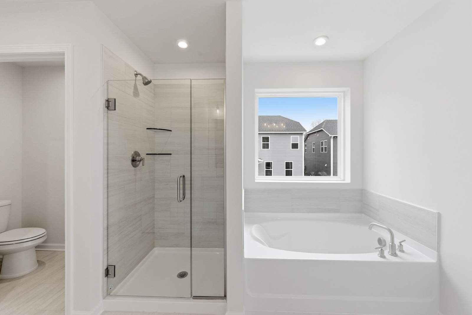 primary bathroom with tile flooring, a glass walk-in shower, and a large soaking tub