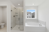 primary bathroom with tile flooring, a glass walk-in shower, and a large soaking tub