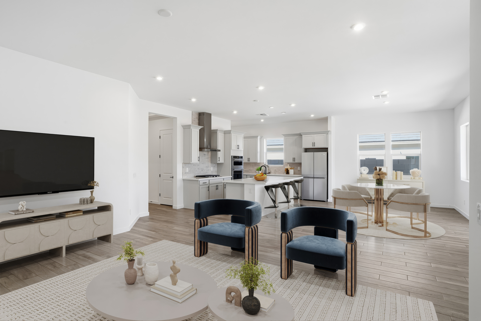 open-concept space with a glass dining table, white chairs, and blue accent chairs