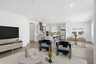 open-concept space with a glass dining table, white chairs, and blue accent chairs