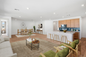open-concept space with a large white couch, a light-brown rug, and green accent chairs