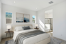 spacious bedroom with large bed, wooden nightstands, and ocean artwork