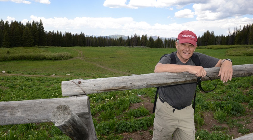 Mike Zoob leans against a fence in front of a field in Wyoming
