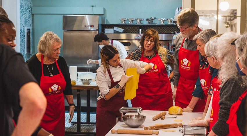 Participants watch an instructor demonstrate in a cooking class