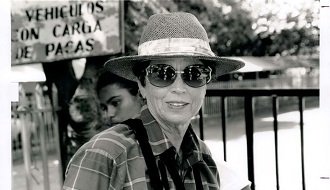 A woman wearing sunglasses and a wide-brim hat smiles at the camera in Costa Rica