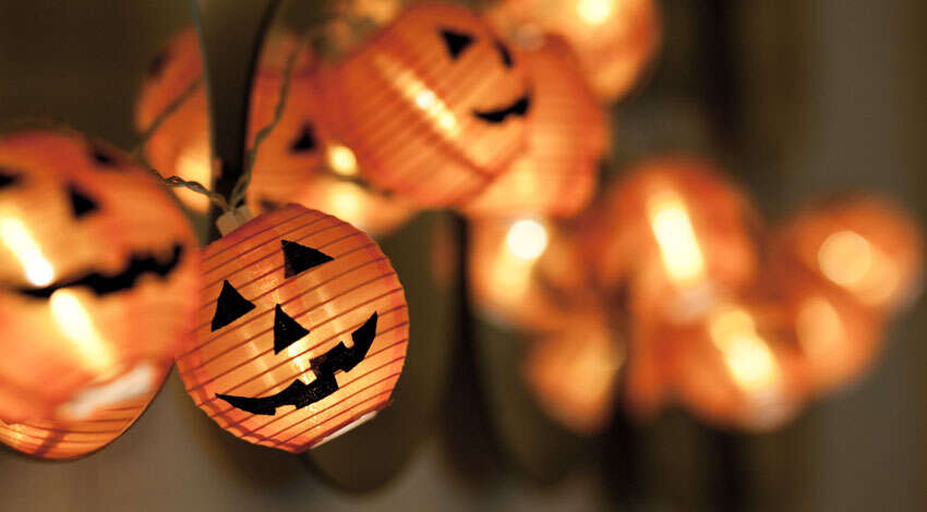 A string of glowing orange jack-o'-lantern Halloween pumpkin lanterns with carved faces.
