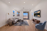 open-concept space with large L-shaped couch, black metal coffee table, and walnut tv console