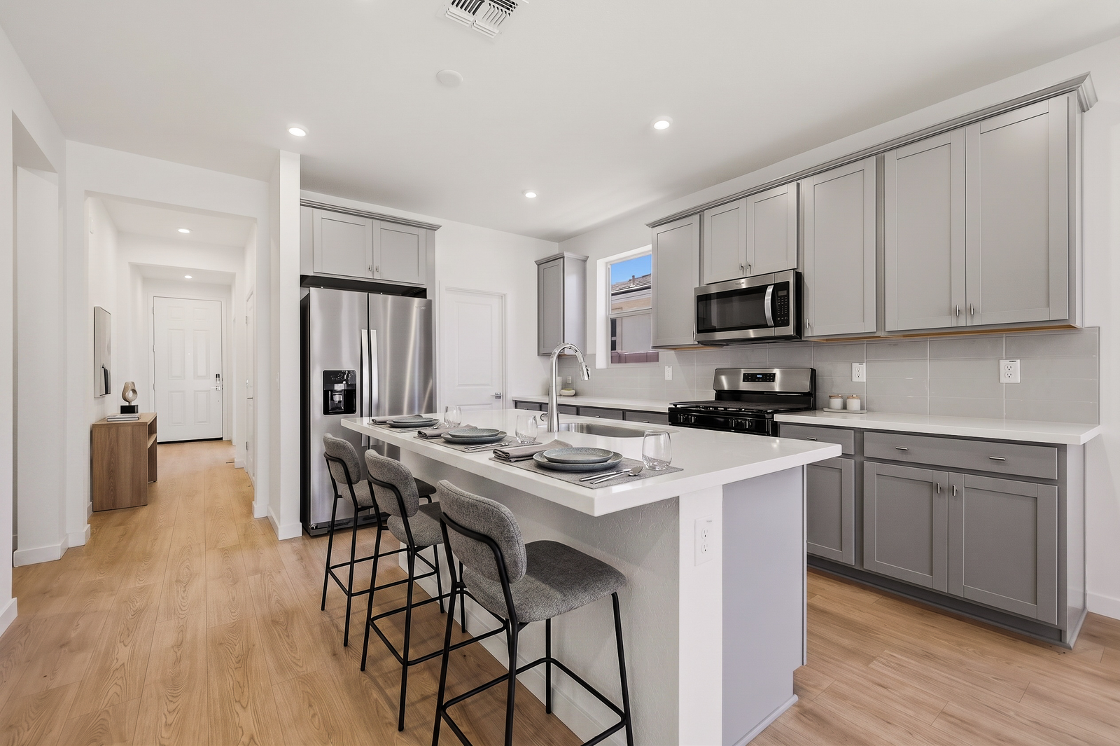spacious kitchen with white quartz countertops, light grey cabinets, and grey barstools