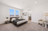 spacious bedroom with a king-sized bed, walnut bedframe, and white accent chair