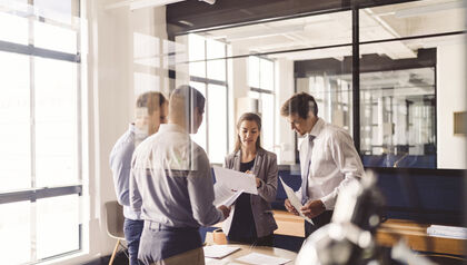 Group of professionals in a meeting room behind a glass wall