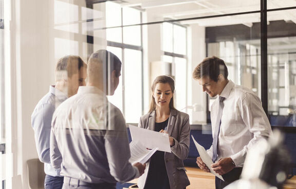 Group of professionals in a meeting room behind a glass wall
