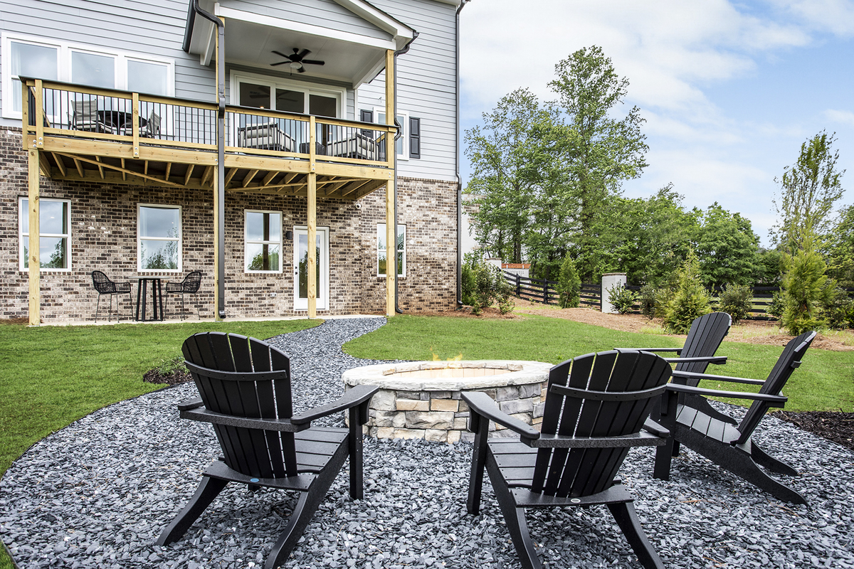 back of 2-story home with deck and firepit