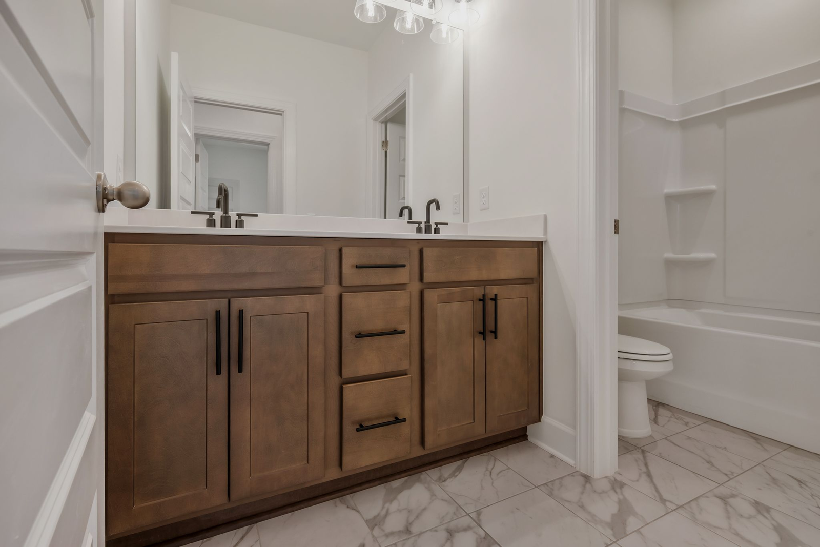 bathroom with tub shower, wood cabinets and black hardware