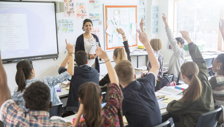 Classroom of teens raising their hands