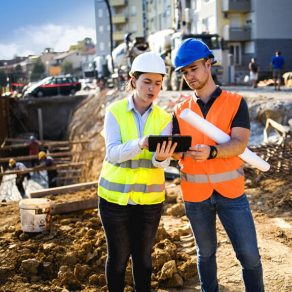 Construction workers discussing plans on tablet