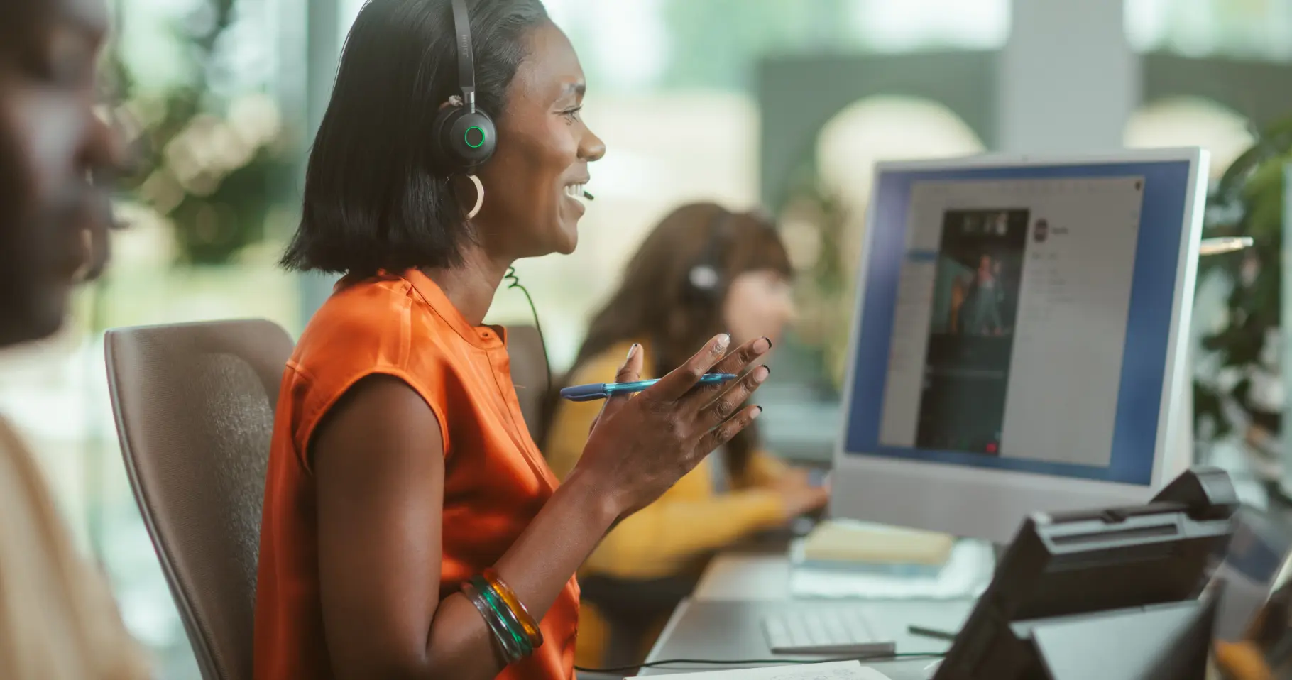 Side view of woman with headset smiling at screen as she uses contact center AI to interact with a customer.