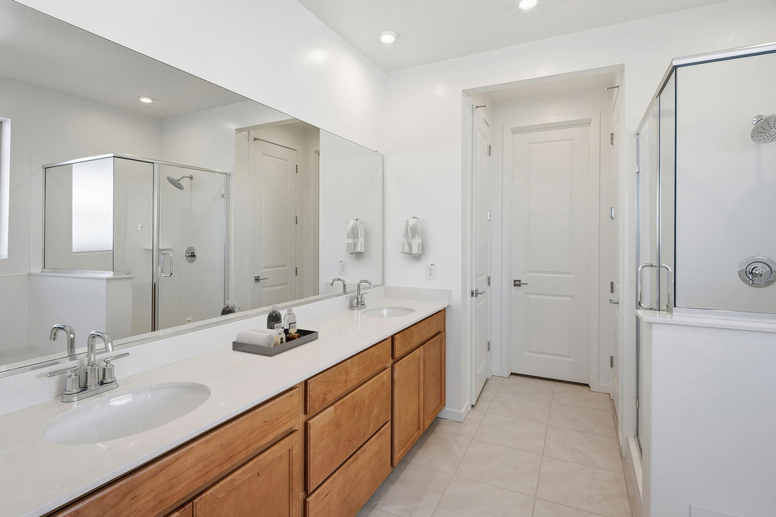 spacious bathroom with light brown cabinets, white countertops, and chrome faucets