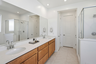 spacious bathroom with light brown cabinets, white countertops, and chrome faucets