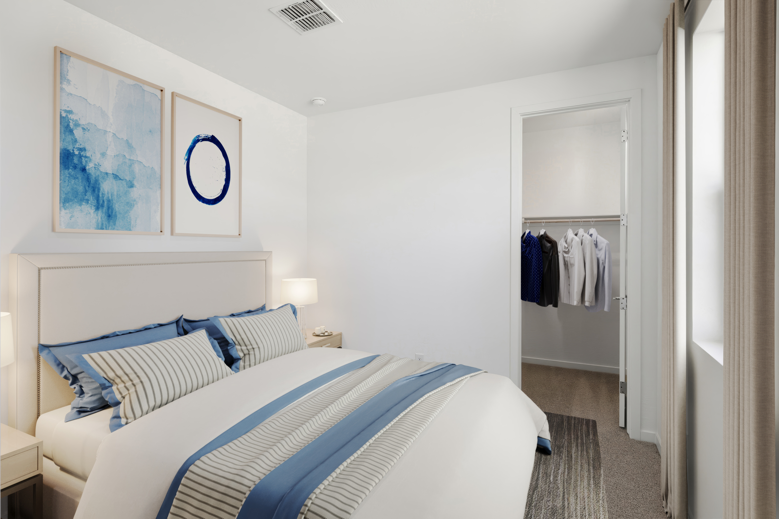 bedroom with a large bed, grey rug, and blue accents on the bed cover and paintings