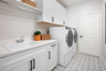 laundry room with tile floors and white cabinets