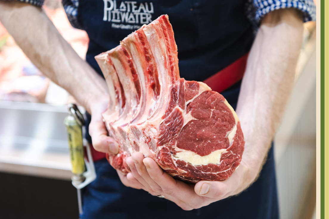 Close up image of butcher holding a rack meat on the bone