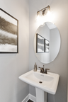 powder room with oval mirror and single standing sink