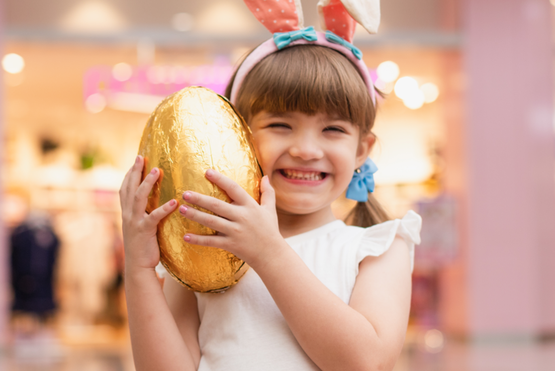Little shopper taking part in Easter retail, hugging an easter egg with bunny ears